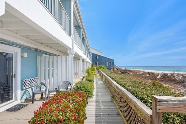 A beachfront property with a covered walkway, outdoor seating, and a view of the ocean.