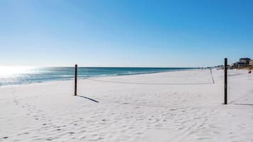Cancha de voleibol de playa con red, arena y cielo despejado.