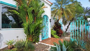 A white building with turquoise accents, a decorative gate, and lush tropical plants. - PalmHousePR Luxury Tropical Villa w/ Private Pool Perfect for Groups San Juan (San Juan)