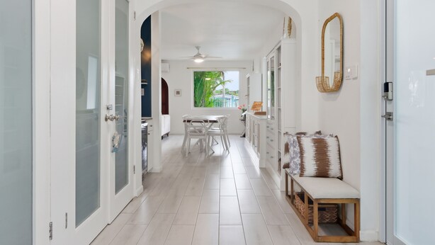 A hallway with a white door, a bench, and a dining area with a table and chairs. - PalmHousePR Luxury Tropical Villa w/ Private Pool Perfect for Groups San Juan (San Juan)