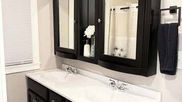 Un baño con dos lavamanos, un espejo grande y armarios negros.