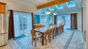 Une cuisine spacieuse avec une longue table à manger, des meubles en bois et des fenêtres de toit.