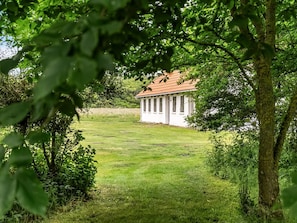 Ein weißes Gebäude mit rotem Dach, umgeben von üppiger Vegetation und Bäumen.