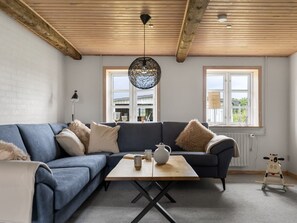 Ein modernes Wohnzimmer mit einer Eckcouch, einem Holztisch und einer Pendelleuchte.
