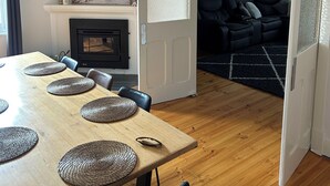 A dining area with a wooden table, woven placemats, and a fireplace.