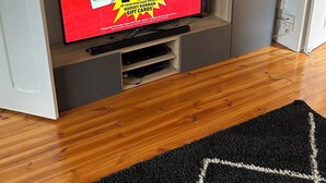 A television displaying a promotional offer, a wooden entertainment unit, and a black rug.