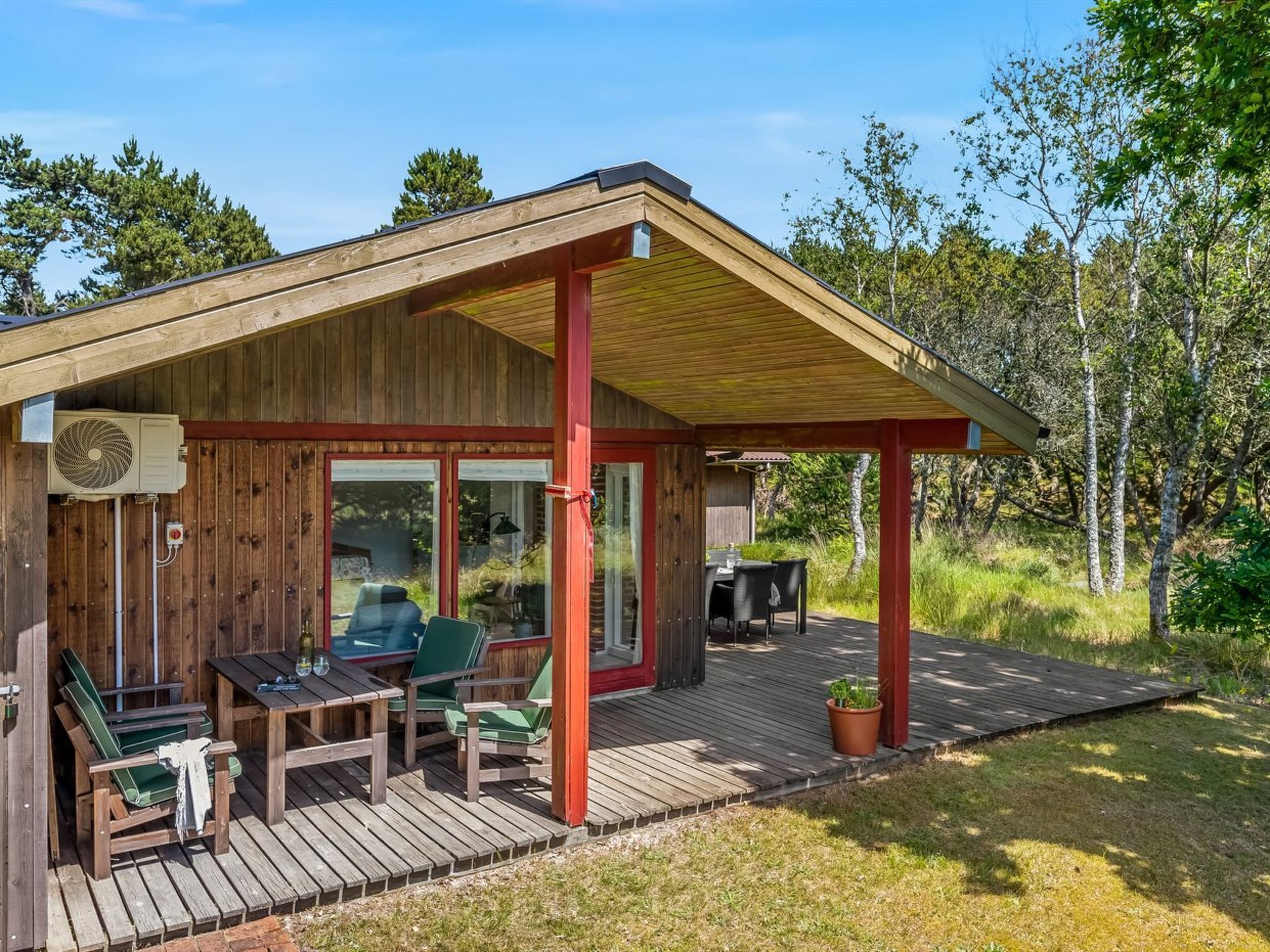 Une cabane en bois dotée d’un patio couvert, de meubles d’extérieur et d’un grand ventilateur.