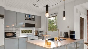 Uma cozinha moderna com ilha central, eletrodomésticos embutidos e iluminação pendente.