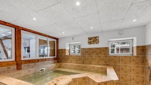 A spa area with a stone-tiled floor, a glass-enclosed hot tub, and a wooden-framed window. - "Blaguna" - 9km to the fjord by Interhome (Tarm)