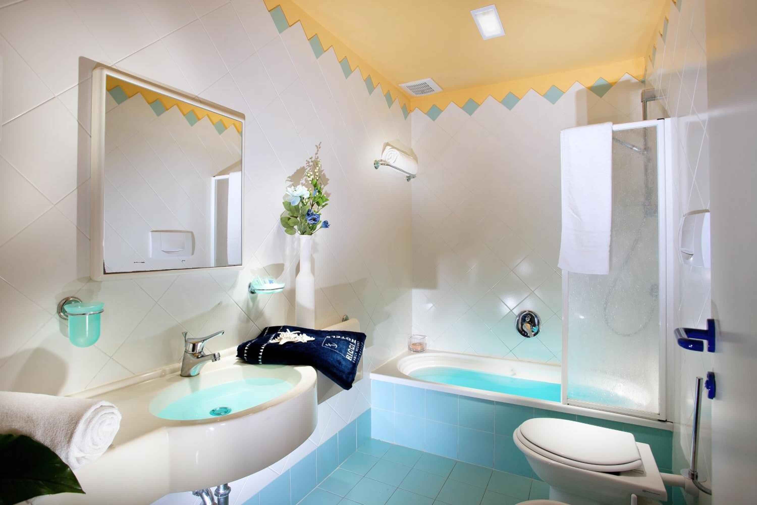 Et badeværelse med vask, spejl, toilet, badekar og bruser.