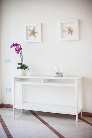 A white console table with a potted plant and a glass container with a starfish. - Hotel Valverde & Residenza (Cesenatico)