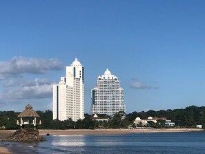 Eine Küstenstadt mit zwei markanten weißen Hochhäusern, einem Strand und einer kleinen, hütteartigen Struktur.