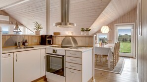 A modern kitchen with a central island, built-in oven, and stainless steel range hood. - "Arold" - 600m to the fjord by Interhome (Lemvig)