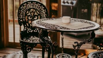Een ronde tafel met een witte kop, een gekleurd vloerkleed en een zwarte ijzeren stoel.
