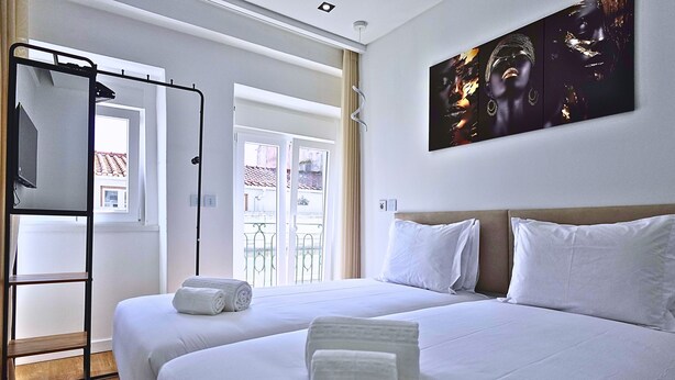 Ein Hotelzimmer mit zwei Betten, einem Fernseher, einem Fenster mit Blick und einem Bild an der Wand.