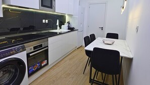Eine kompakte Küche mit Waschmaschine, Mikrowelle und einer Essecke mit Tisch und Stühlen.