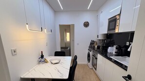 Eine kompakte Küche mit Waschmaschine, Mikrowelle und einer Essecke mit Tisch und Stühlen.