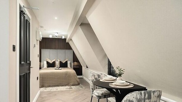 Ein Schlafzimmer mit Bett, Nachttisch und einer kleinen Essecke mit Tisch und Stühlen.