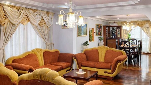 Ein geräumiges Wohnzimmer mit Essbereich, ausgestattet mit einer Kristallleuchtre, Sofas und einer Bar.