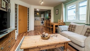 Ett mysigt vardagsrum med en soffa, ett soffbord med dekorativa föremål, en tv och en matplats med stolar och ett bord.