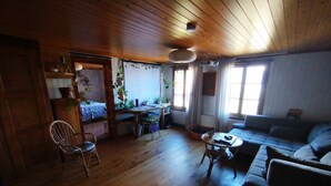 A cozy living room with a wooden ceiling, a sofa, a dining table with chairs, and a kitchen area with a window. - Lakeview Chalet 1 , Därligen (Darligen)