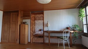 A room with a wooden ceiling, a woven partition, a wooden desk, a chair, and a window with plants. - Lakeview Chalet 1 , Därligen (Darligen)