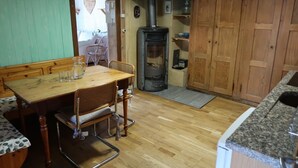 A wooden dining table with chairs, a bench, a wood-burning stove, and a kitchen counter. - Lakeview Chalet 1 , Därligen (Darligen)