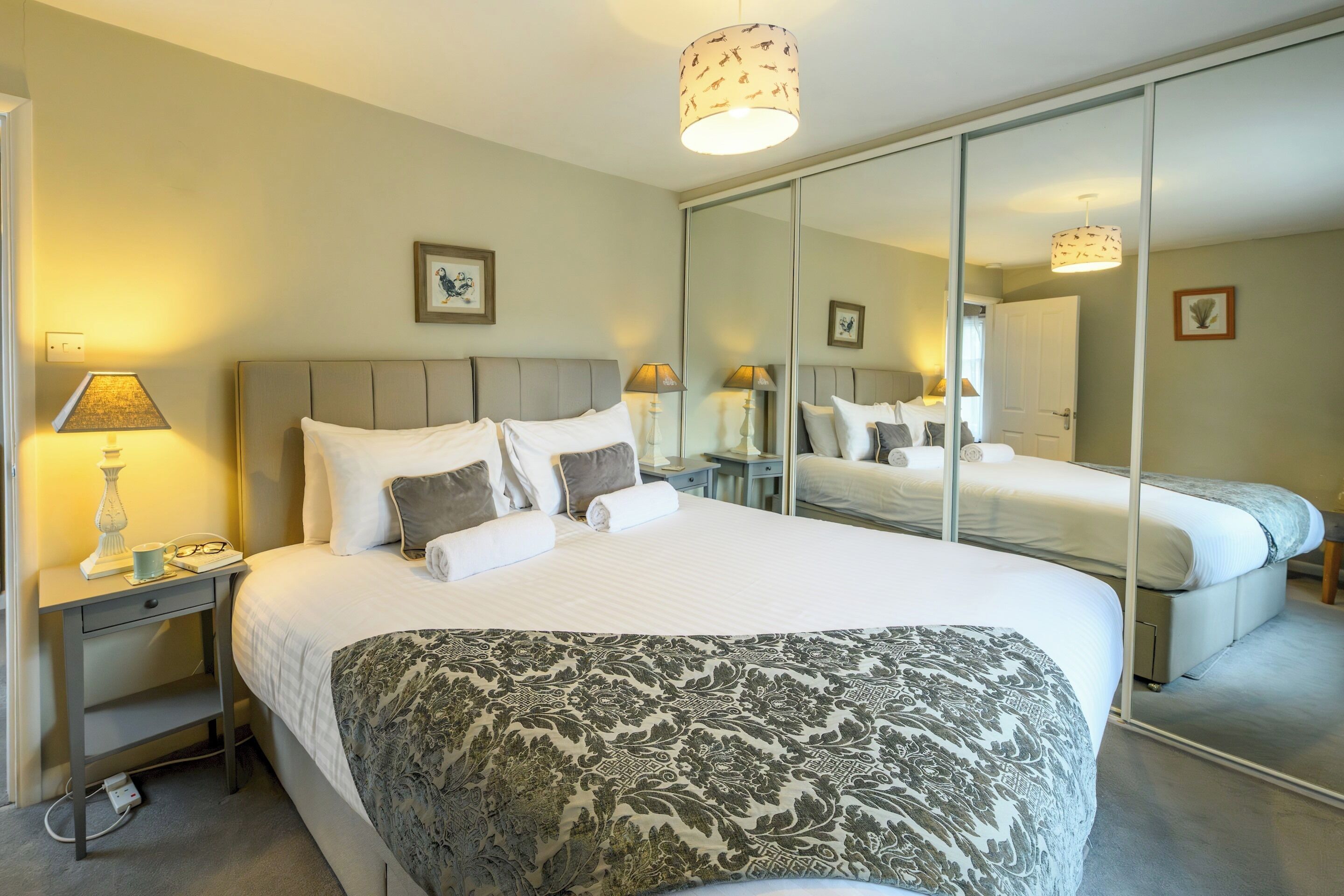 Ett hotellrum med en stor säng, sängbord, en spegel och en lampa.