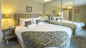 A hotel room with a large bed, bedside tables, a mirror, and a lamp. - Charming 2-Bed Townhouse with Parking, Near Centre - Pass the Keys (Shrewsbury)