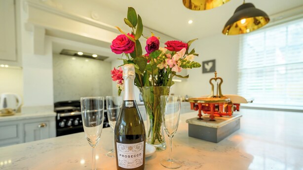 A kitchen with a marble countertop, a bottle of Prosecco, and a vase of flowers. - Charming 2-Bed Townhouse with Parking, Near Centre - Pass the Keys (Shrewsbury)