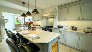 A modern kitchen with a central island, black chairs, a dining table, and a view of the garden. - Charming 2-Bed Townhouse with Parking, Near Centre - Pass the Keys (Shrewsbury)