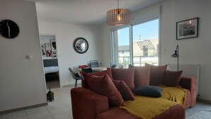 Una sala de estar con sofá, mesa de comedor y un amplio ventanal.