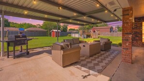 Eine Terrasse im Freien mit überdachtem Bereich, einem Grill und Gartenmöbeln.