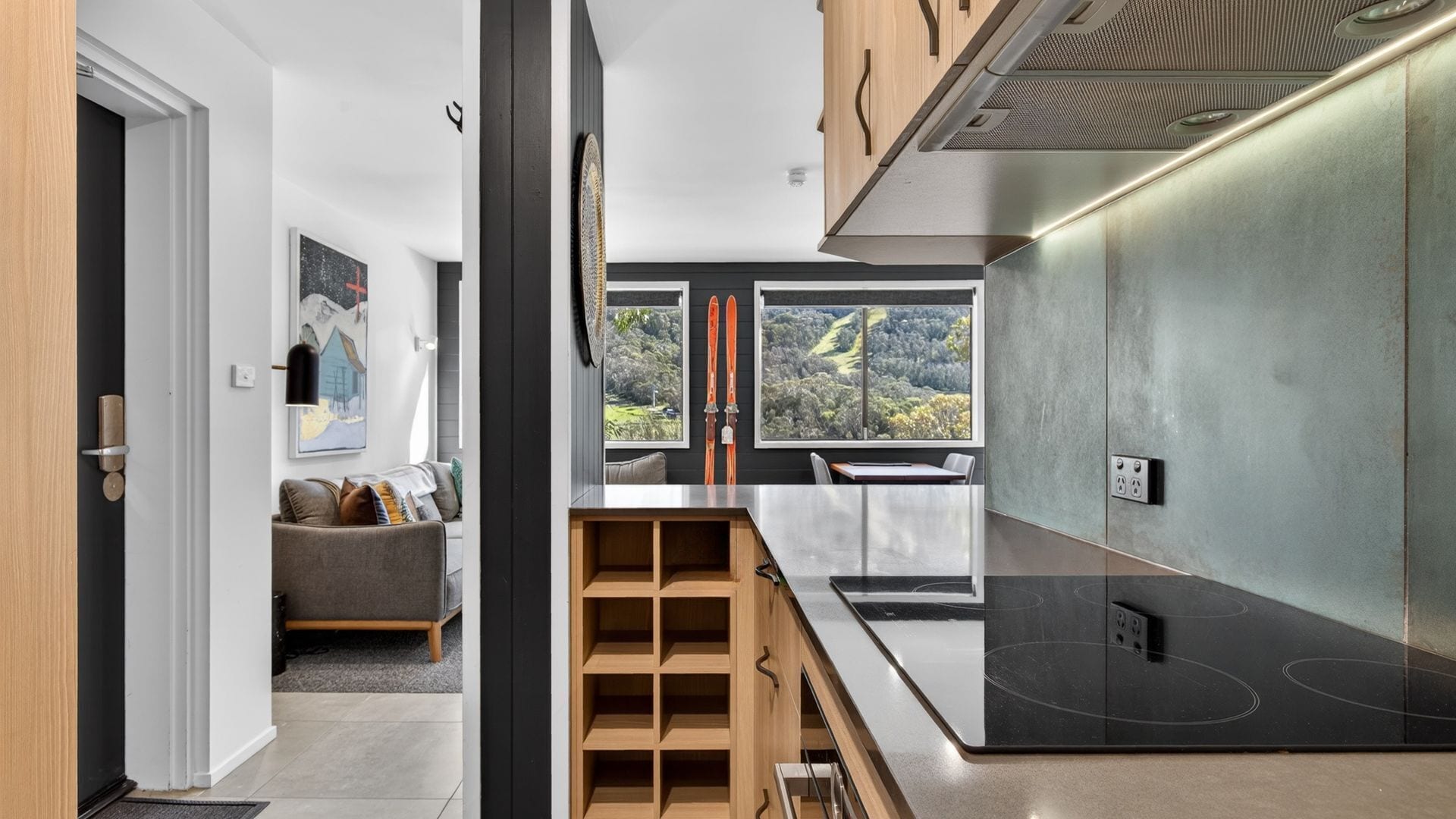A modern kitchen with a large window, built-in shelves, and a sleek stove.
