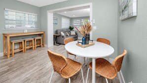 A dining area with a round table, wicker chairs, a bench, and a sofa in the background. - Cottage Pool Across From the Beach (Madeira Beach)