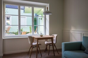 Une pièce avec une fenêtre, une table, deux chaises et un canapé.