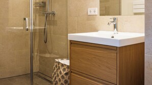 Un bagno moderno con box doccia in vetro, mobile lavabo in legno e uno specchio grande.