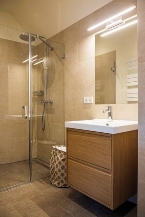 A modern bathroom with a glass shower enclosure, a wooden vanity, and a large mirror. - Suite 03 - light-filled and airy dream apartment (Österreich)