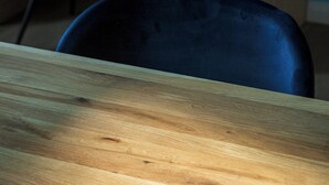 Un tavolo di legno con una sedia sullo sfondo.