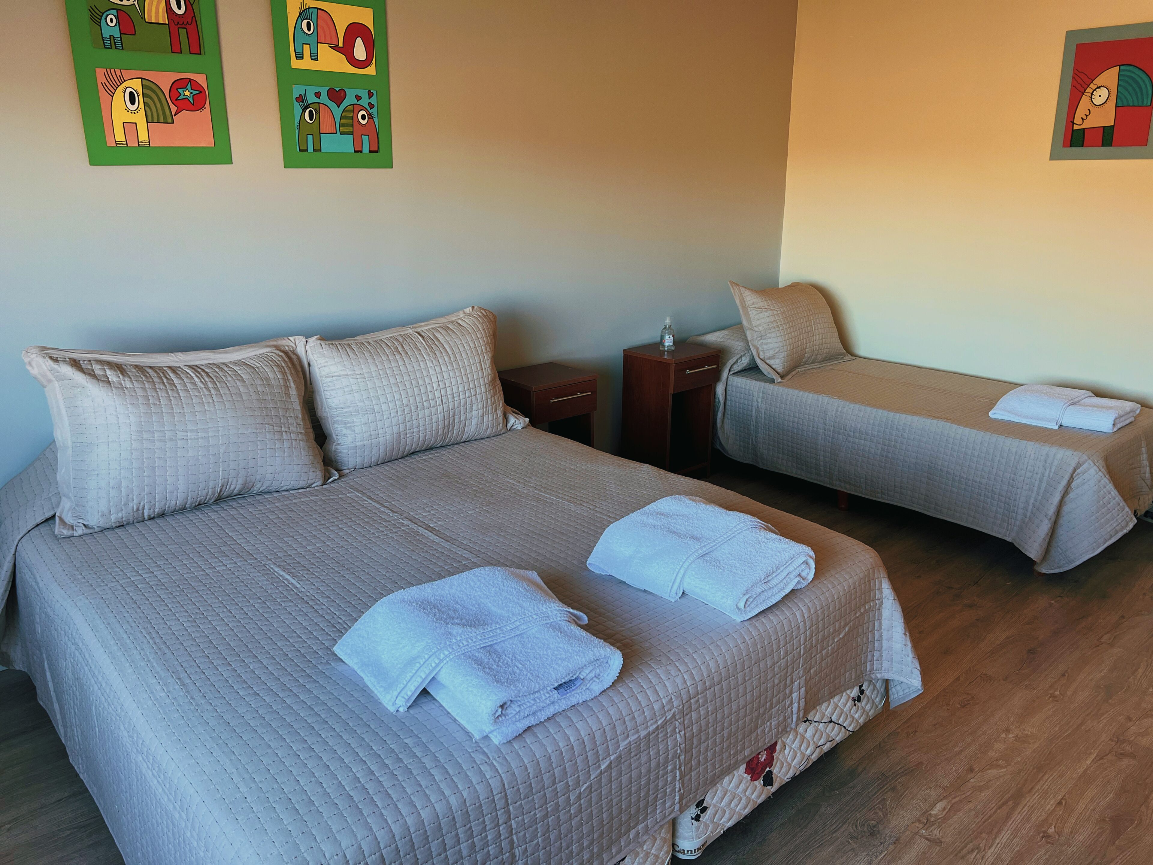 Ein Hotelzimmer mit zwei Betten, einem Nachttisch und Bildern an den Wänden.