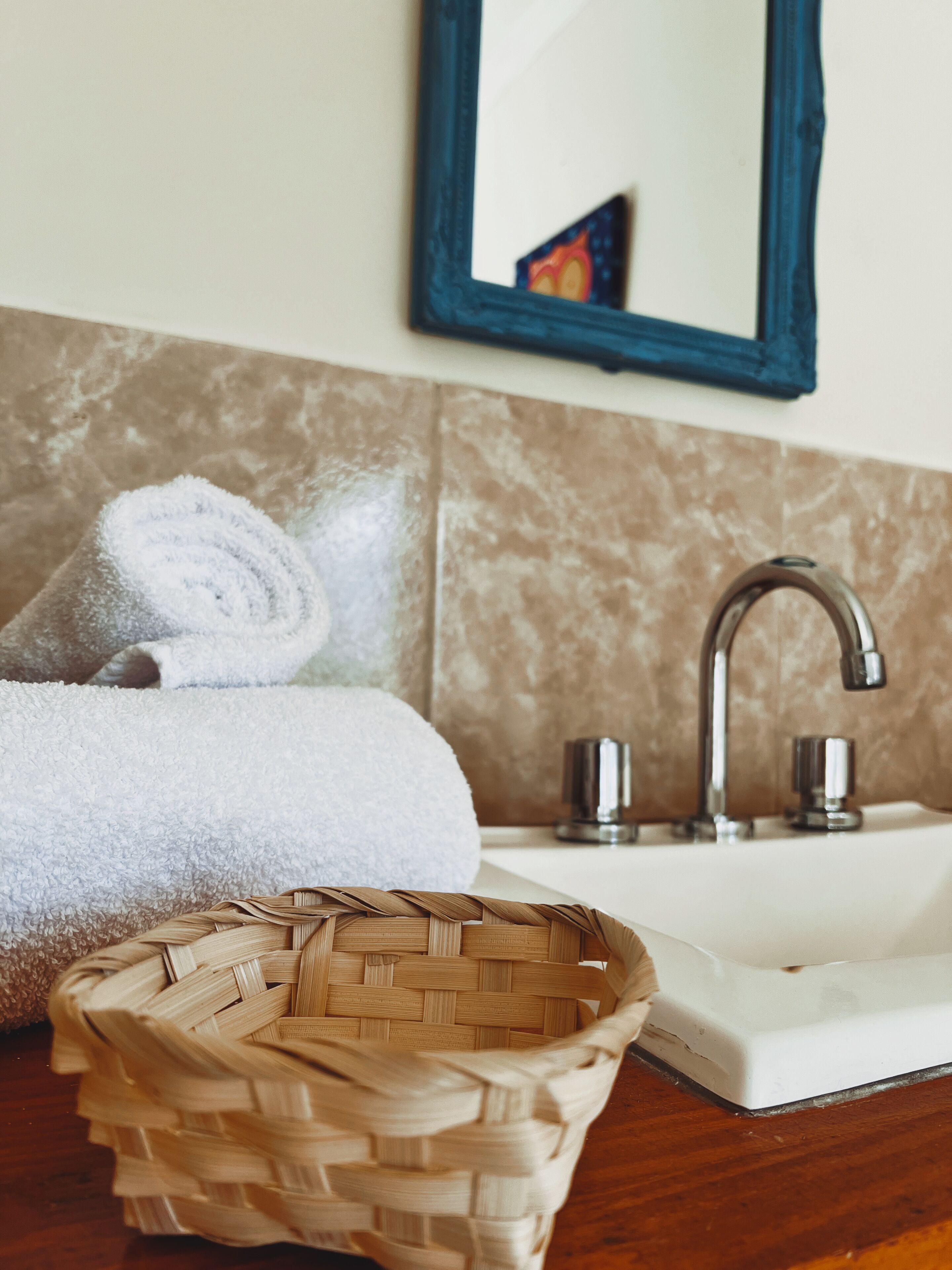 A bathroom with a sink, a mirror, a towel, and a woven basket.