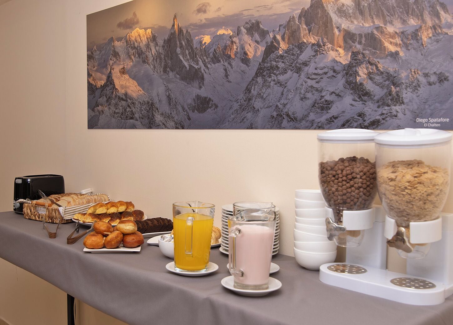 Un bufé de desayuno con bollería, una máquina de café y un dispensador de zumo.