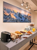 Ein reichhaltiges Frühstücksbuffet mit einem Bergmotiv, einem Toaster und einer Auswahl an Gebäck.