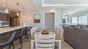 Eine moderne Küche mit Bar, einem Esstisch mit Stühlen und einem Wohnbereich mit einer Couch.
