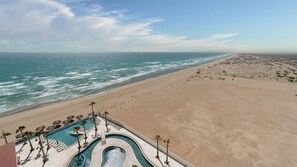 A resort with a swimming pool, palm trees, and a view of the beach and ocean. - A Style Of Its Own 2 Encantame Viento 1104 (Puerto Peñasco)