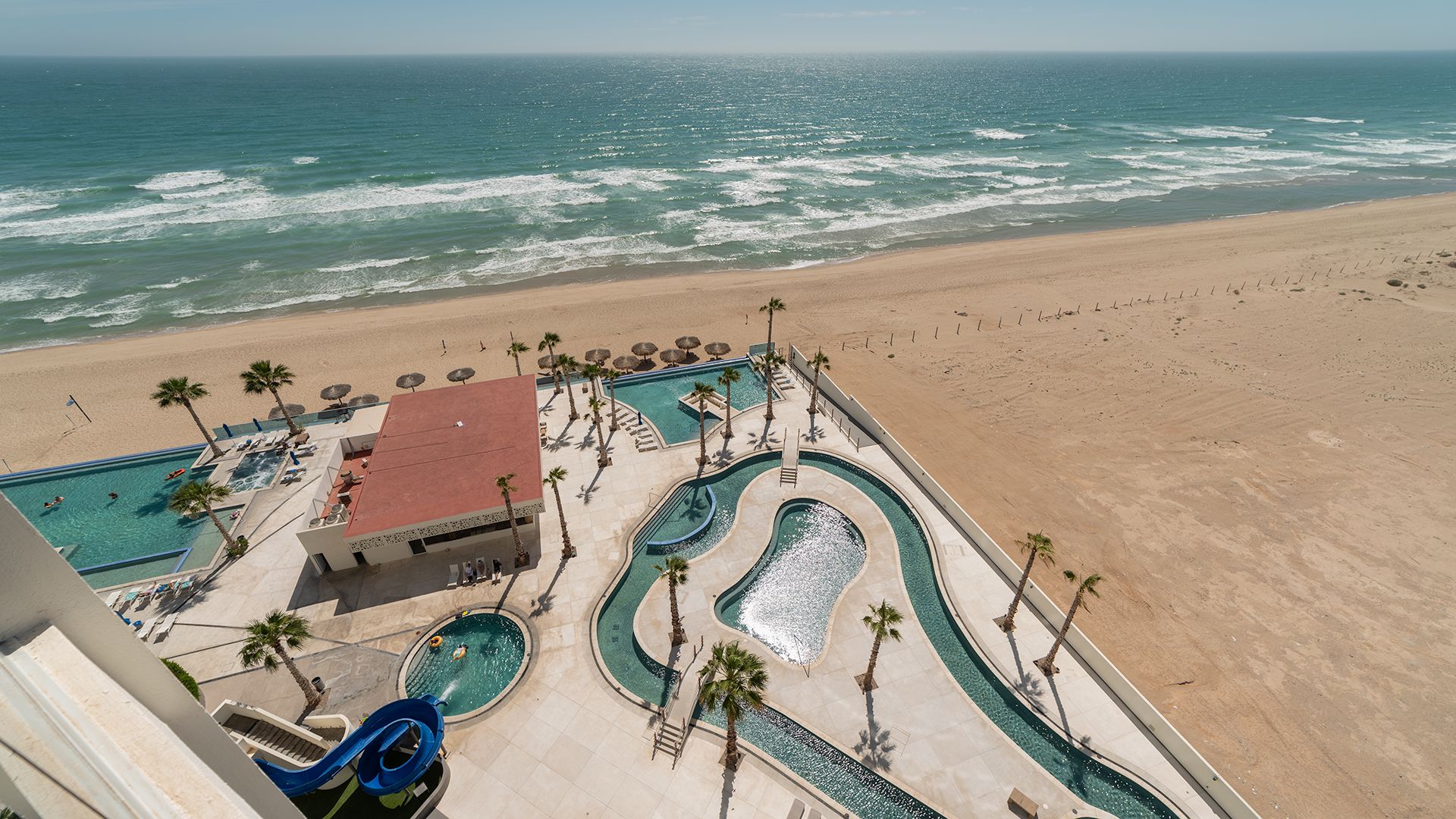 Un complexe hôtelier doté d’une piscine, d’un toboggan aquatique et d’une plage.