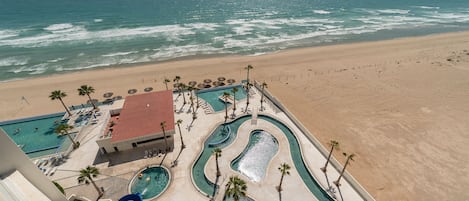 Een resort met een zwembad, een glijbaan en een strand.