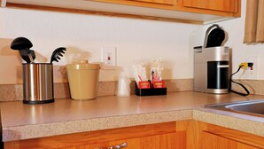 A kitchen counter with a coffee maker, a container with utensils, a salt shaker, and a set of condiment packets. - Kitchenette 1: Cozy Woodsy Suite w/  Kitchen – Your Adventure Basecamp (Florence)