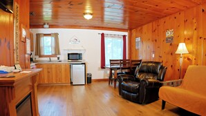 A wooden cabin interior with a kitchen, dining area, and seating. - Kitchenette 1: Cozy Woodsy Suite w/  Kitchen – Your Adventure Basecamp (Florence)