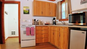 A kitchen with wooden cabinets, a microwave, a stove, and a refrigerator. - Kitchenette 1: Cozy Woodsy Suite w/  Kitchen – Your Adventure Basecamp (Florence)